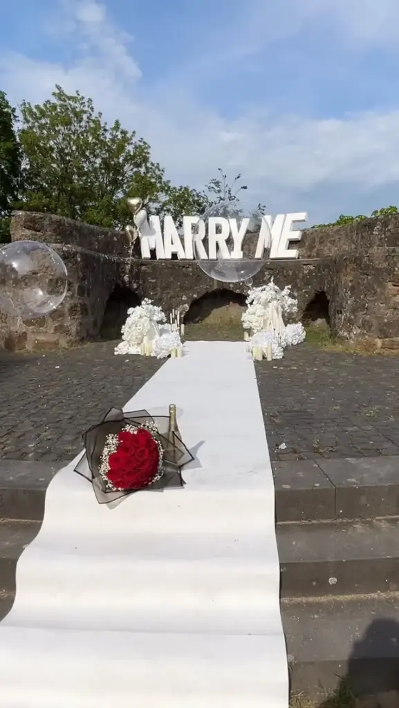Heiratsantrag mit weißem Läufer, MARRY-ME-Buchstaben und roten Rosen – Fam.Deko